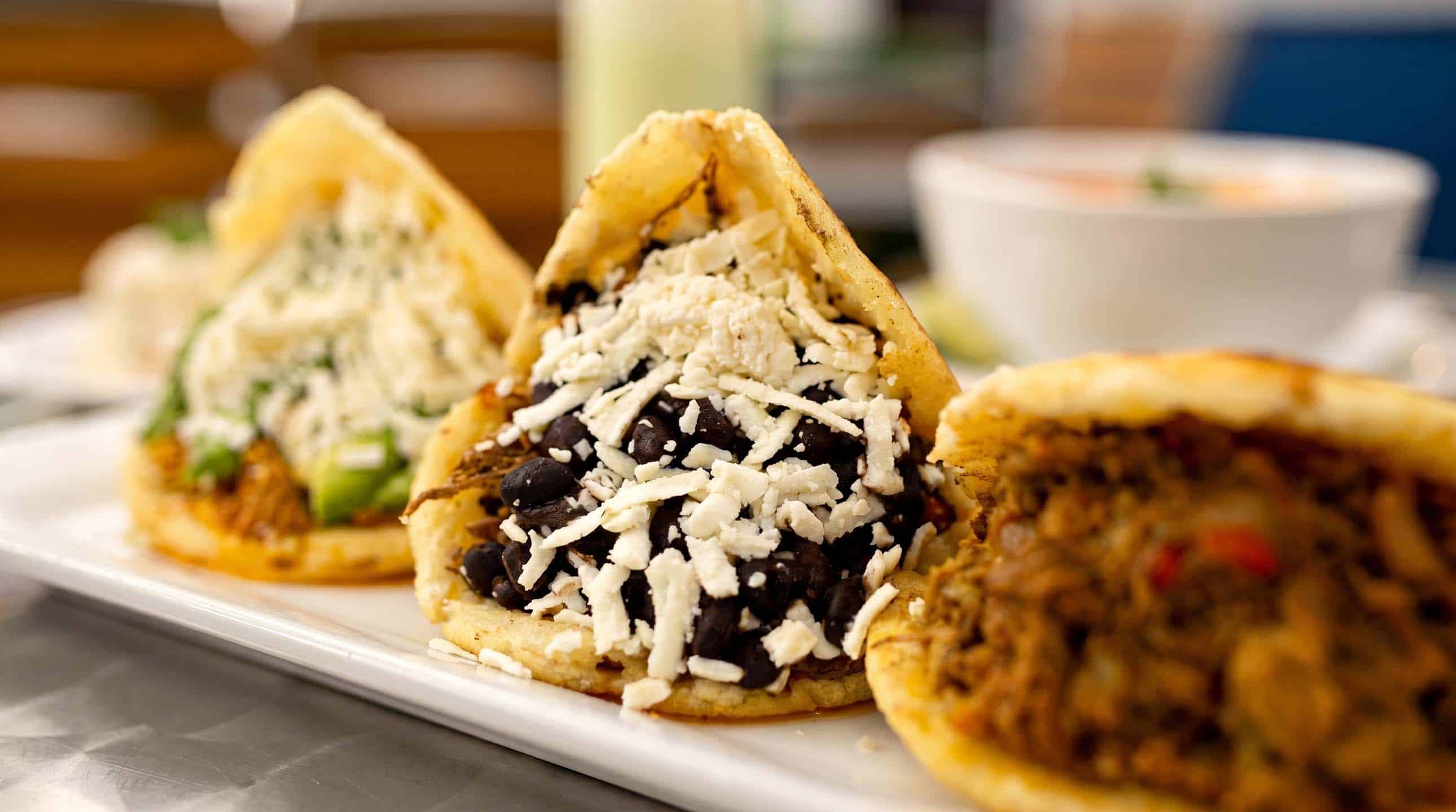 Trio of warm Venezuelan arepas filled with shredded beef, black beans, and white cheese.